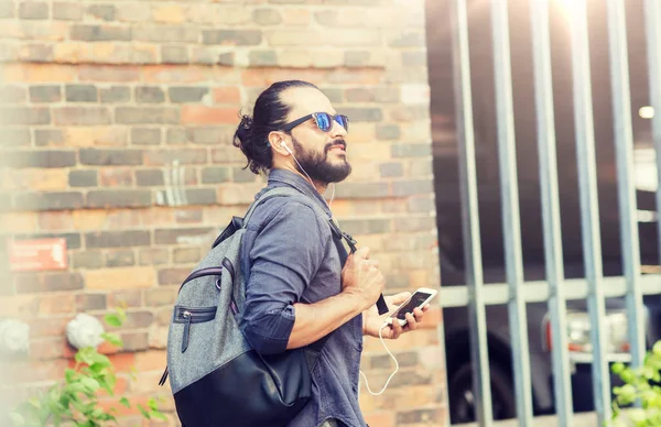 Homme avec écouteurs et smartphone marche en ville — Photo