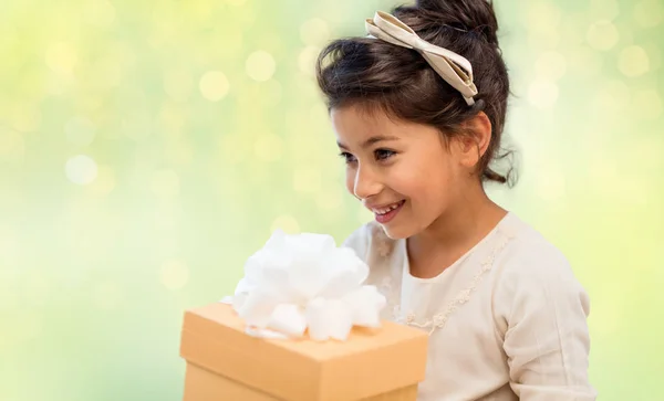 Menina feliz com caixa de presente sobre luzes verdes — Fotografia de Stock