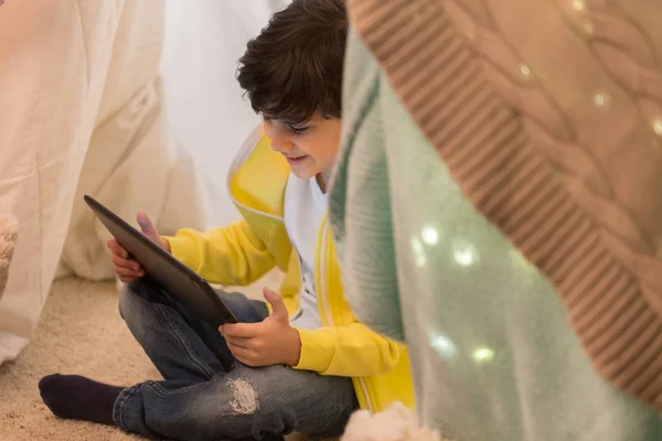 Маленький мальчик с планшетным ПК в детской палатке дома — стоковое фото