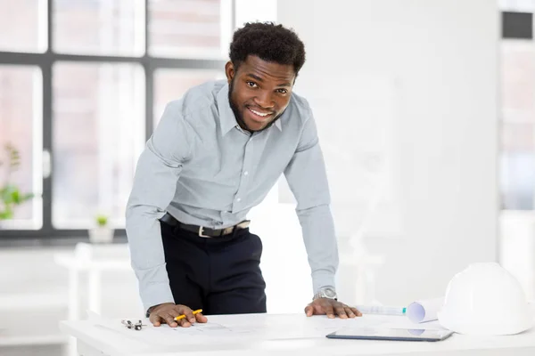 Smiling african architect with blueprint at office — Stock Photo, Image