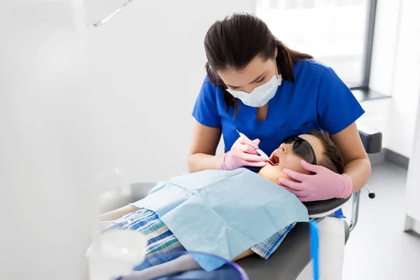 Dentista verificando dentes de criança na clínica odontológica — Fotografia de Stock