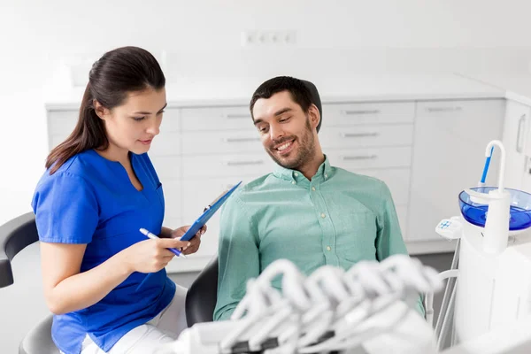 Dentista e paciente discutindo tratamento odontológico — Fotografia de Stock