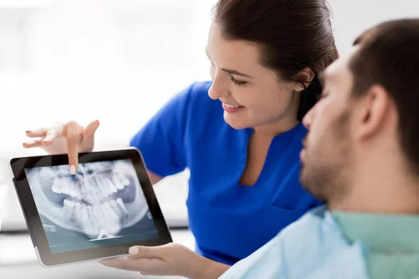 Dentista e paciente com raio-x dos dentes no tablet pc — Fotografia de Stock