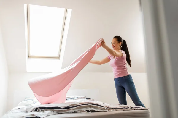 Mujer feliz o ama de casa haciendo la cama en casa —  Fotos de Stock