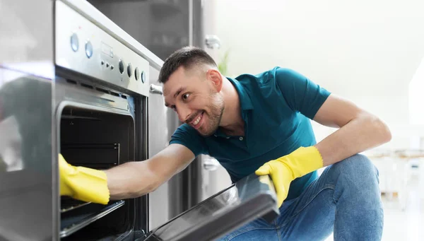 Man met doek schoonmaken in oven thuis keuken — Stockfoto