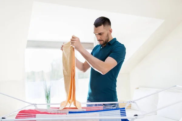 Hombre tomando ropa de secadero en casa — Foto de Stock