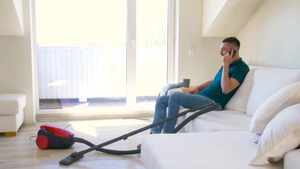 Мужчина звонит по смартфону после уборки дома — стоковое видео
