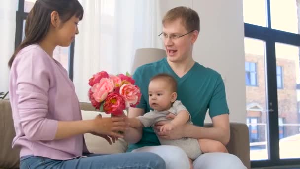 Familia feliz con flores y bebé niño en casa — Vídeos de Stock