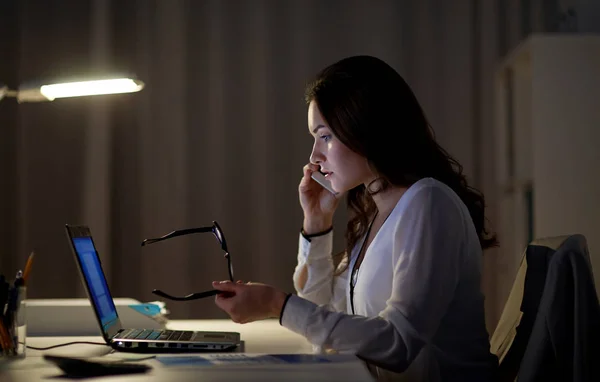 Женщина с ноутбуком звонит на смартфон в офисе — стоковое фото
