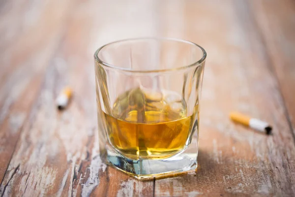 Vaso de alcohol en la mesa y colillas de cigarrillos — Foto de Stock