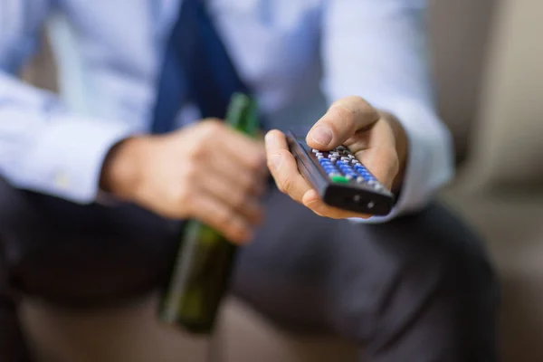 Close up of man with tv remote drinking beer — Stock Photo, Image