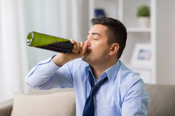 Mannelijke alcoholische wijn drinken uit flesje thuis — Stockfoto