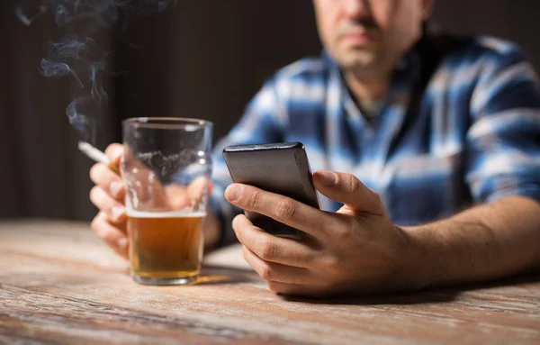 Hombre con celular bebiendo alcohol y fumando — Foto de Stock