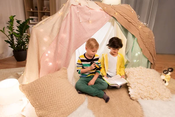 Ragazzi felici leggere libro in tenda per bambini a casa — Foto Stock