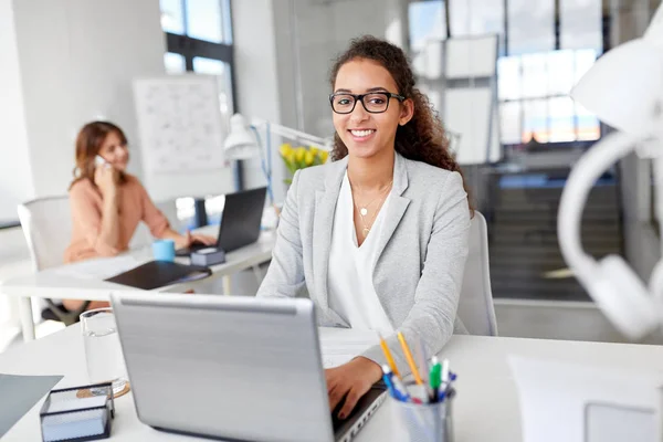 Lykkelig forretningskvinne med bærbar datamaskin som arbeider på kontoret – stockfoto