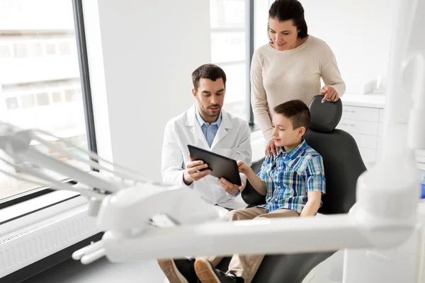 Dentist showing tablet pc to kid at dental clinic — Stock Photo, Image