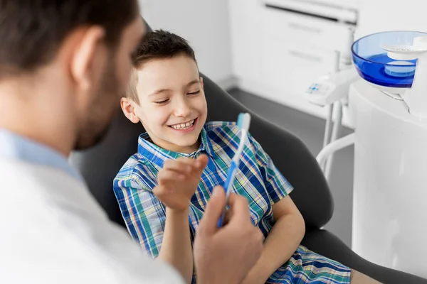 Dentista dándole cepillo de dientes a un paciente infantil en la clínica — Foto de Stock