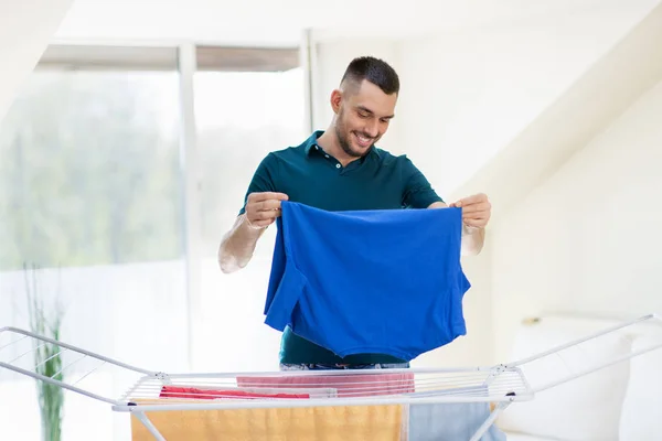 Sorrindo homem com lavandaria e secagem rack em casa — Fotografia de Stock