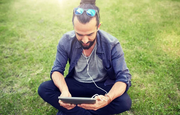 Férfi fülhallgató és smartphone ül a fűben — Stock Fotó