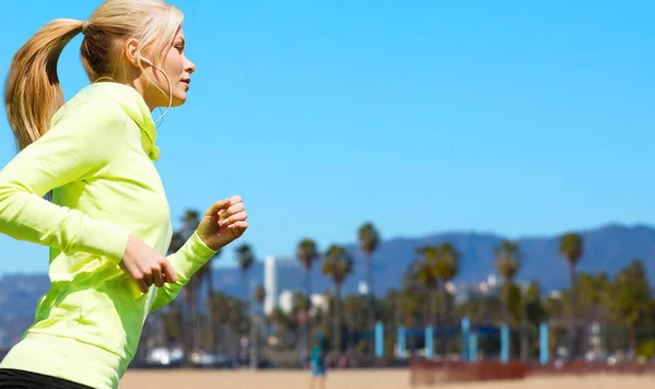 Woman with earphones running over venice beach — Stock Photo, Image