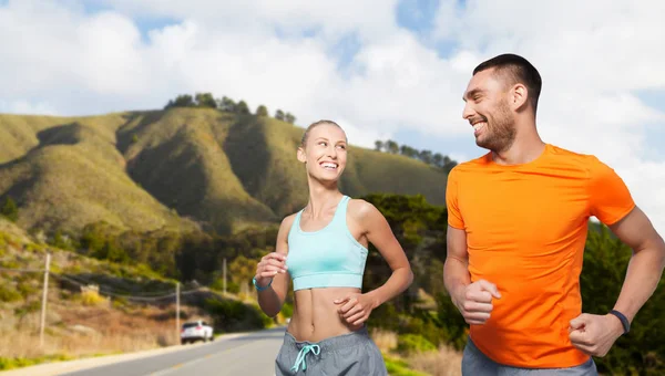 Sonriente pareja corriendo sobre grandes colinas sur — Foto de Stock