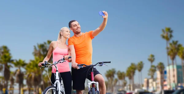 Casal com bicicletas tirando selfie por smartphone — Fotografia de Stock