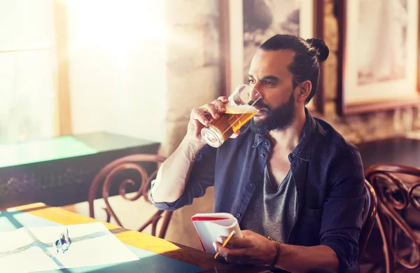 Homem com caderno bebendo cerveja em bar ou pub — Fotografia de Stock