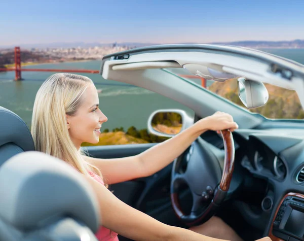 Mulher dirigindo carro conversível sobre portão dourado — Fotografia de Stock