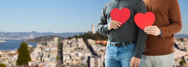 Close up of happy male couple holding red hearts — Stock Photo, Image