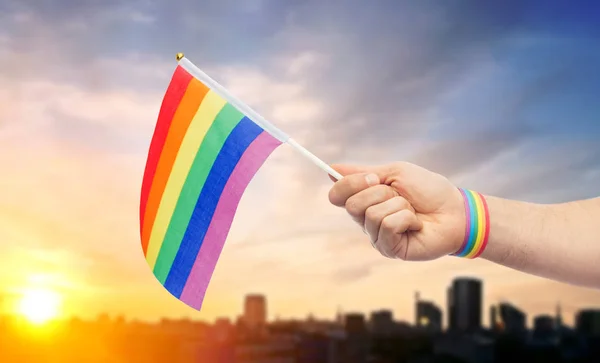 Hand with gay pride rainbow flag and wristband — Stock Photo, Image