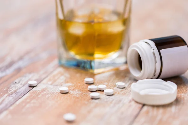 Glas Alkohol und Tabletten auf dem Tisch — Stockfoto