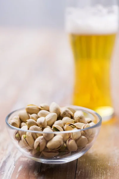 Kacang pistachio dalam mangkuk dan segelas bir draught — Stok Foto
