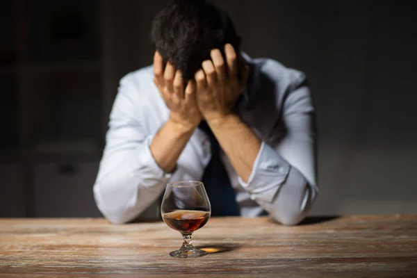 Opilý muž se sklenkou alkoholu na stole v noci — Stock fotografie