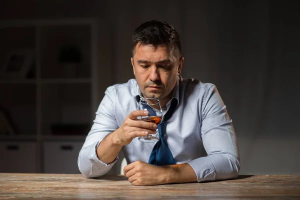 Drunk man with glass of alcohol on table at night — Stock Photo, Image