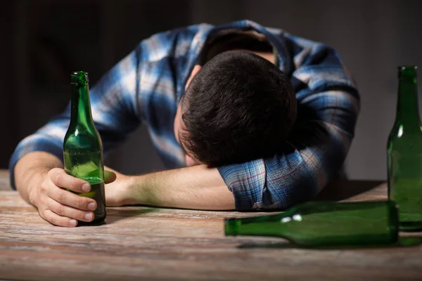 Drunk man with beer bottles on table at night — Stock Photo, Image