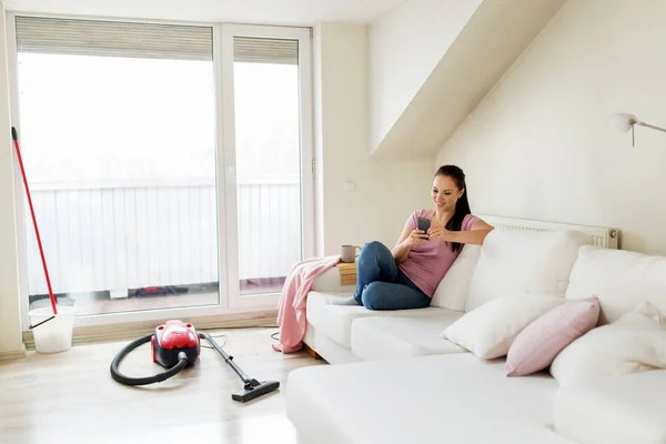 Woman with smartphone and vacuum cleaner at home — Stock Photo, Image