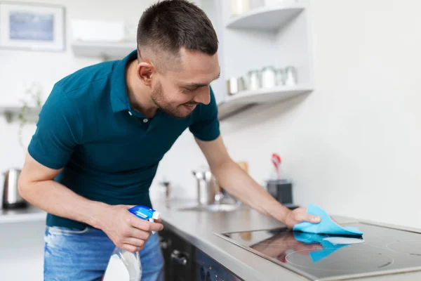 Man met doek reinigen kookplaat op huis keuken — Stockfoto