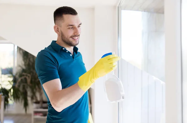 Mannen i gummihandskar rengöring fönster med spray — Stockfoto