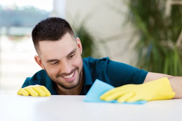 Усміхнений чоловік прибирає стіл з тканиною вдома — стокове фото