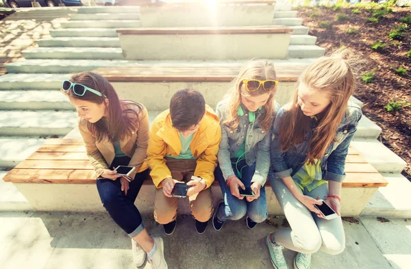 Amigos adolescentes felices con teléfonos inteligentes al aire libre — Foto de Stock