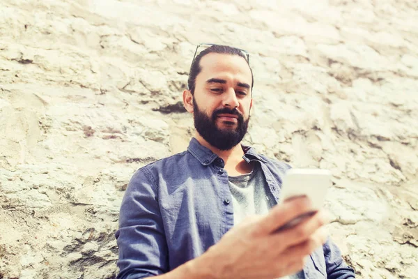 Hombre mensaje de texto en el teléfono inteligente en la pared de piedra — Foto de Stock