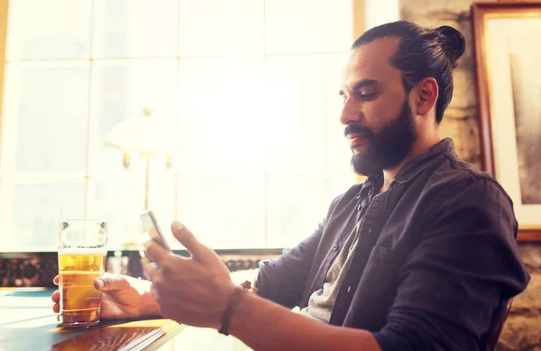 Uomo con smartphone che beve birra al bar o pub — Foto Stock