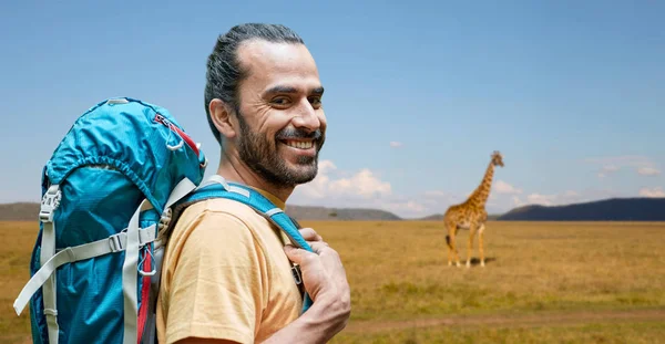 Uomo sorridente con zaino sopra savana africana — Foto Stock