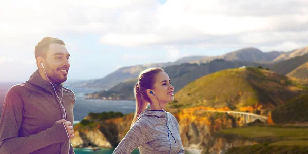 Coppia con auricolari che corre sopra big sur coast — Foto Stock