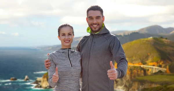 Sorridente coppia in abiti sportivi mostrando pollici in su — Foto Stock