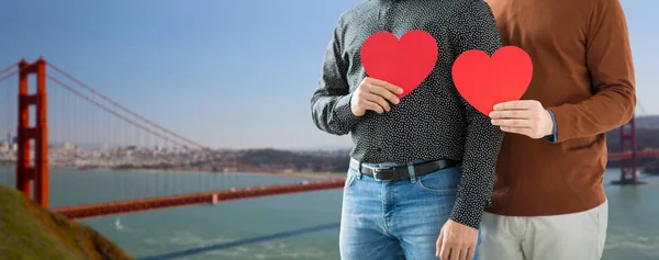 Close up of happy male couple holding red hearts — Stock Photo, Image