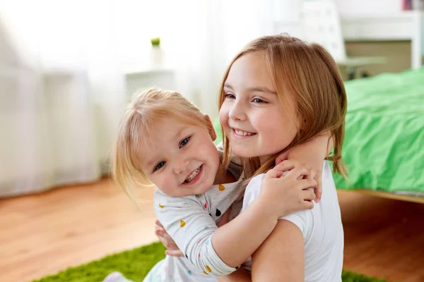 Happy little girls or sisters hugging at home — Stock Photo, Image