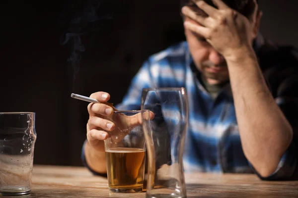 Пьяный мужчина пьет алкоголь и курит сигарету — стоковое фото