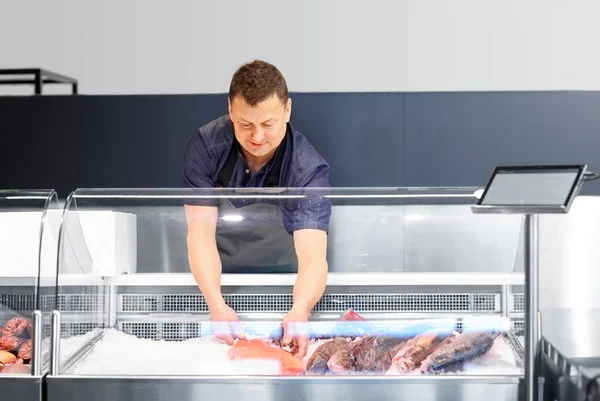 Manliga säljare med skaldjur på fisk butik kylskåp — Stockfoto