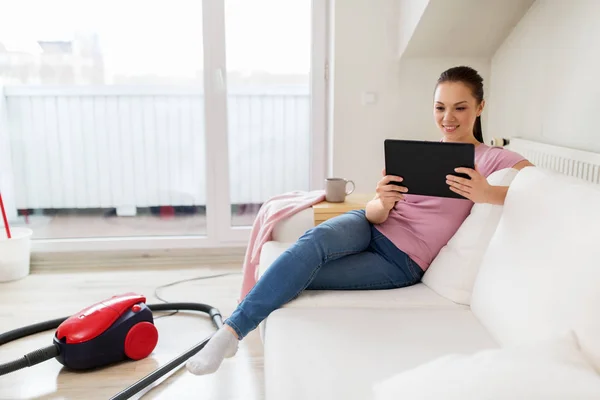 Mujer con tableta PC y aspiradora en casa — Foto de Stock